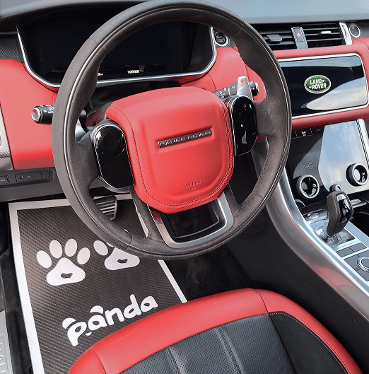 Detailed interior of a automobile with red and black leather seats and steering wheel, cleaned by Panda Hub mobile car detailing service.