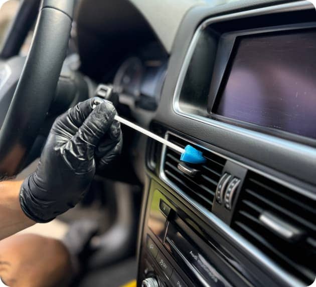 Detailer cleaning car air vents with a swab during interior detailing