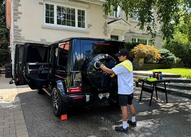 Detailing specialist hand washing black SUV during mobile auto detailing service
